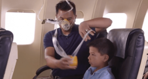 Adult wearing an oxygen mask placing an oxygen mask on a child