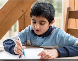 boy writing at a table