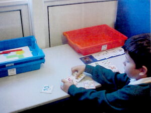 a small boy sitting at a table using the picture exchange communication system