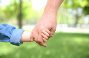 closeup of a child and adult holding hand
