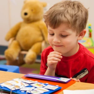 A young boy looks at the array of pictures in his communication book